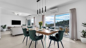 A modern living room with a sofa, dining table, chairs, and a TV. - Apartment Luxury Wellness (Makarska)