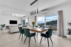 Ein modernes Wohnzimmer mit Sofa, Esstisch, Stühlen und Fernseher.
