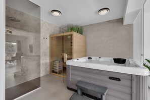 Ein modernes Badezimmer mit Whirlpool, einer Duschkabine aus Glas und einem Holzkabinett.