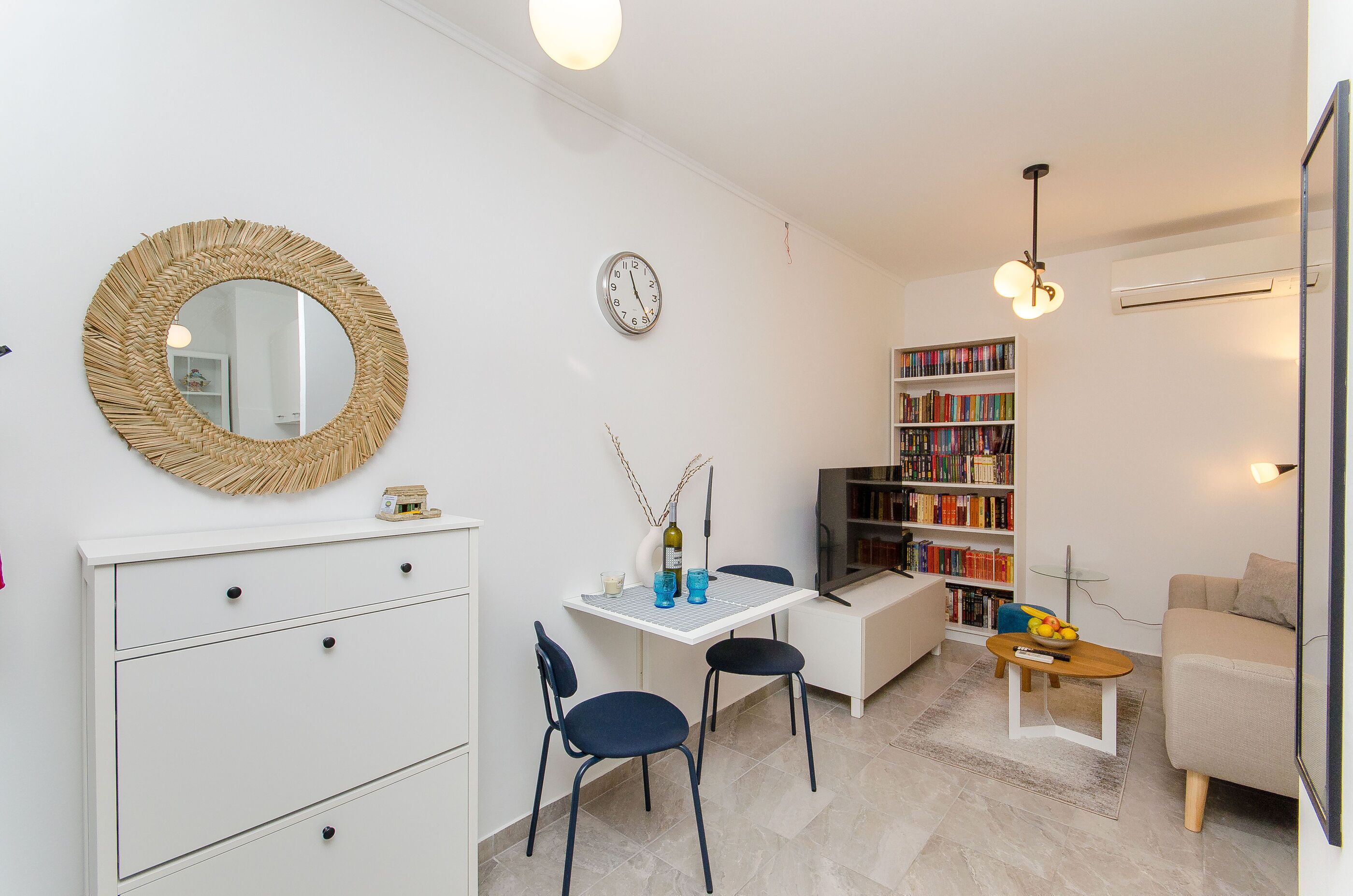 A compact living space with a dining area, a bookshelf, a sofa, and a TV.
