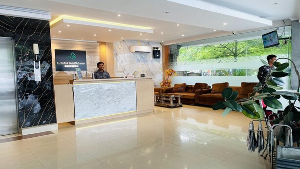 A hotel reception area with a marble reception desk, a seating area with sofas, and a large window offering a view of greenery.