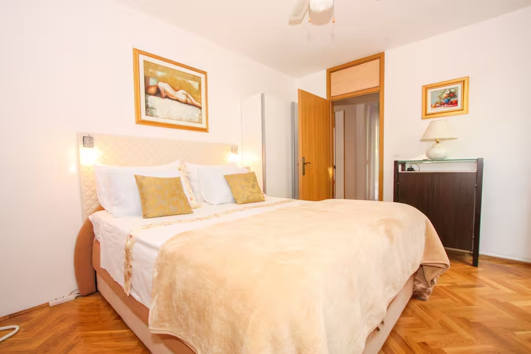 A bedroom with a bed, a bedside table, a lamp, and a door.