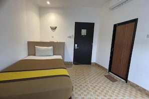 A hotel room with a bed, a door, and a wall-mounted light fixture.