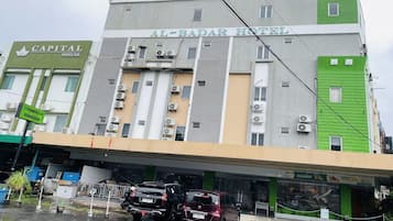 Un hôtel à plusieurs étages, doté de systèmes de climatisation et disposant d’un parking avec des voitures.