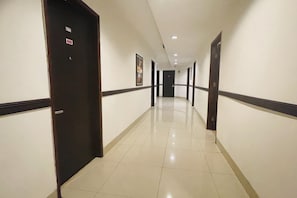 Un couloir d’hôtel avec des portes, un sol carrelé et un plafond doté d’un éclairage encastré.