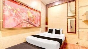 Een hotelkamer met een groot bed, een schilderij aan de muur en een spiegel boven het bed.
