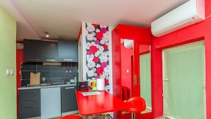 A compact kitchen with a red table, two red chairs, a microwave, and a small refrigerator. - Apartments Urban Stone Escape (Split)