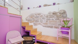 A staircase with a stone wall, a chair, a table, and a potted plant. - Apartments Urban Stone Escape (Split)