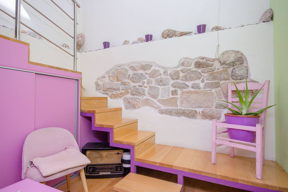 A staircase with a stone wall, a chair, a table, and a potted plant.