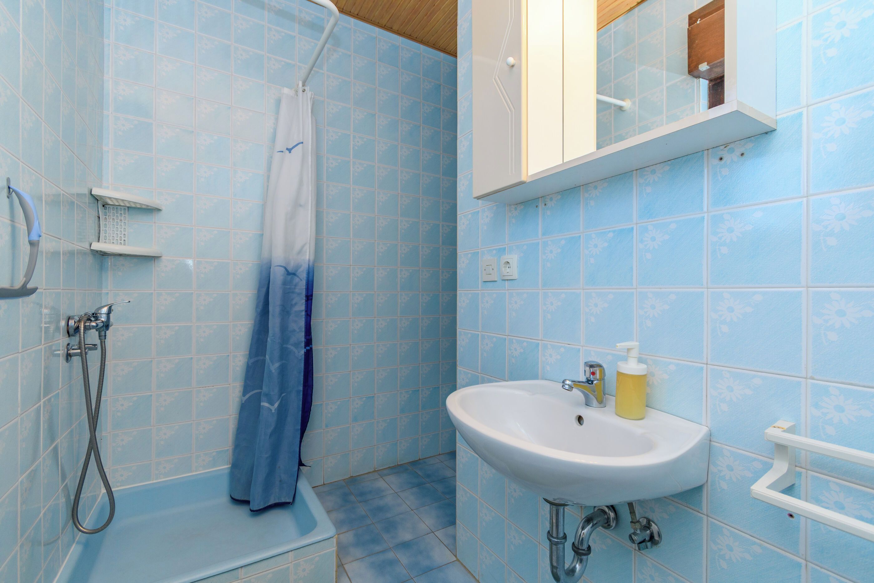 A bathroom with a shower, a sink, and a mirror.