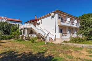 Una casa de dos pisos con balcón, escalera y jardín.