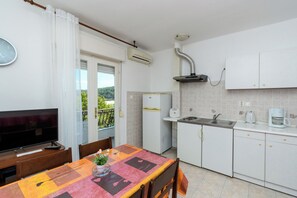 Une cuisine équipée d’un téléviseur, d’une table à manger, de chaises et offrant une vue sur la verdure environnante.