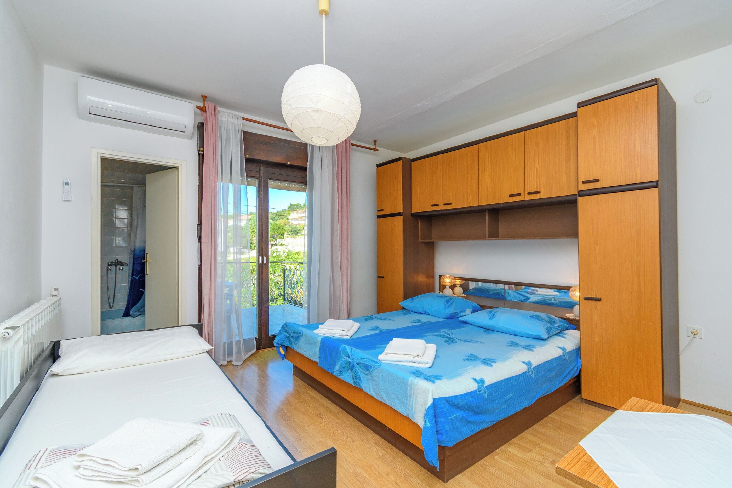 A bedroom with a bed, a bedside table, a wardrobe, and a bathroom with a shower.