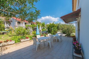 Une terrasse avec des meubles d’extérieur, des plantes en pot et un ciel d’un bleu éclatant.