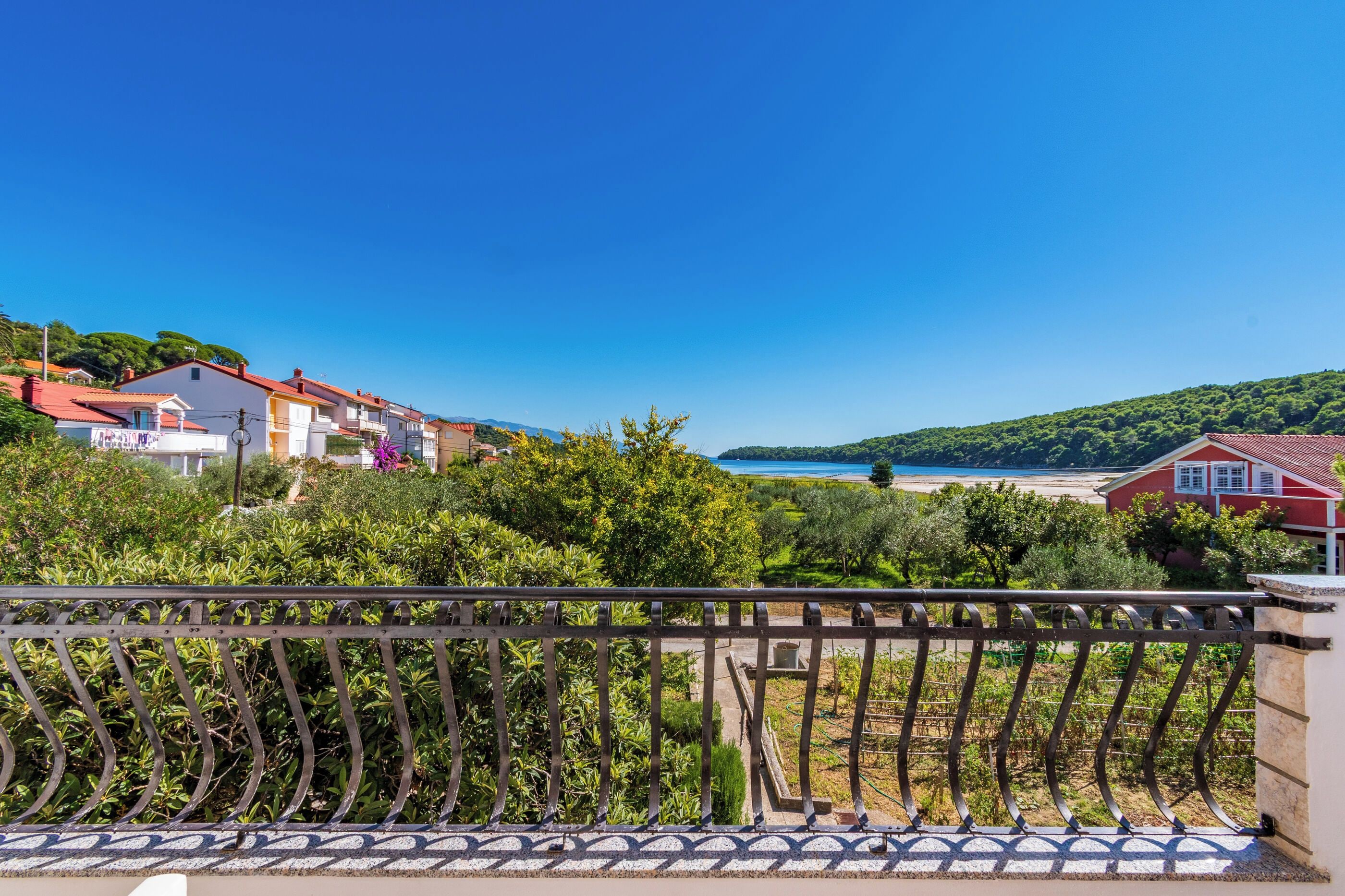 A coastal residential area with houses, a clear blue sky, and a view of the sea.
