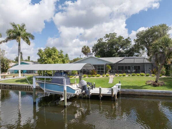 A boat docked at a marina with a house in the background. - Waterfront Pool Home w/ Gulf Access+Dock Sleeps 10 (Port Charlotte)