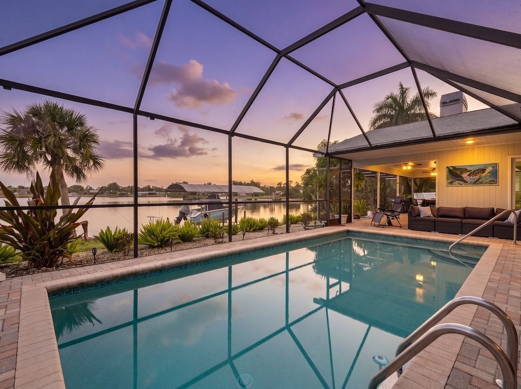 Un espace piscine offrant une vue dégagée sur l’eau, entouré d’une structure en verre, et un coin salon avec vue sur l’eau.