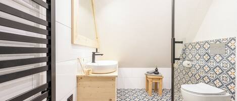 A bathroom with a wooden vanity, a sink, a toilet, and a shower area.
