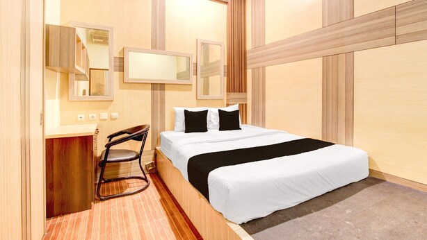 A hotel room with a bed, two bedside tables, a chair, a desk, and a mirror. - Luxury Deluxe DBL Retreat W/ Free WiFi and Parking (Yogyakarta)