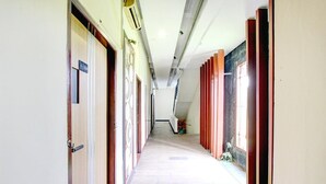 A long hallway with doors on both sides, a tiled floor, and a ceiling with exposed beams. - Luxury Deluxe DBL Retreat W/ Free WiFi and Parking (Yogyakarta)
