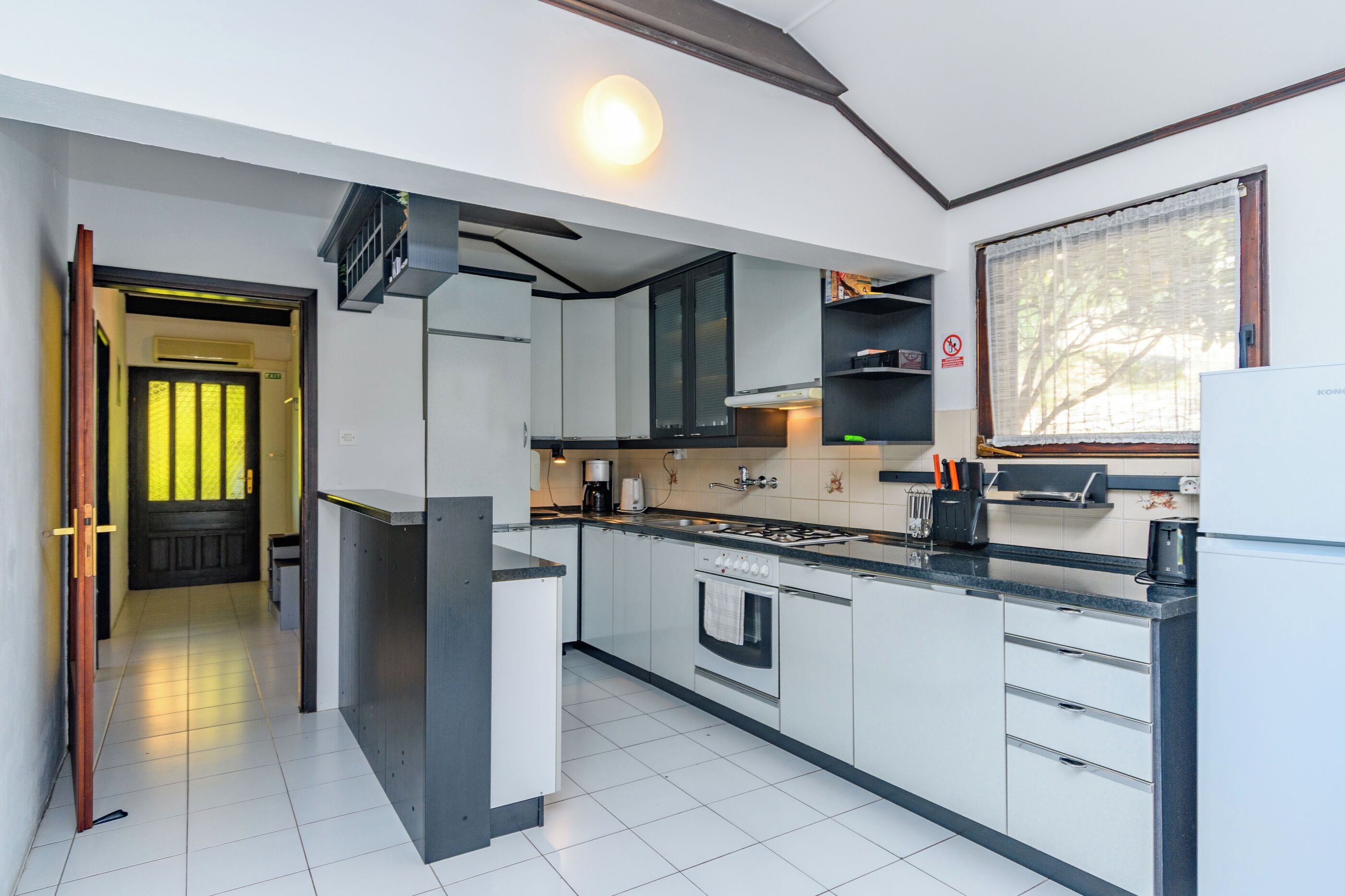 A modern kitchen with white cabinetry, a built-in oven, and a stove.
