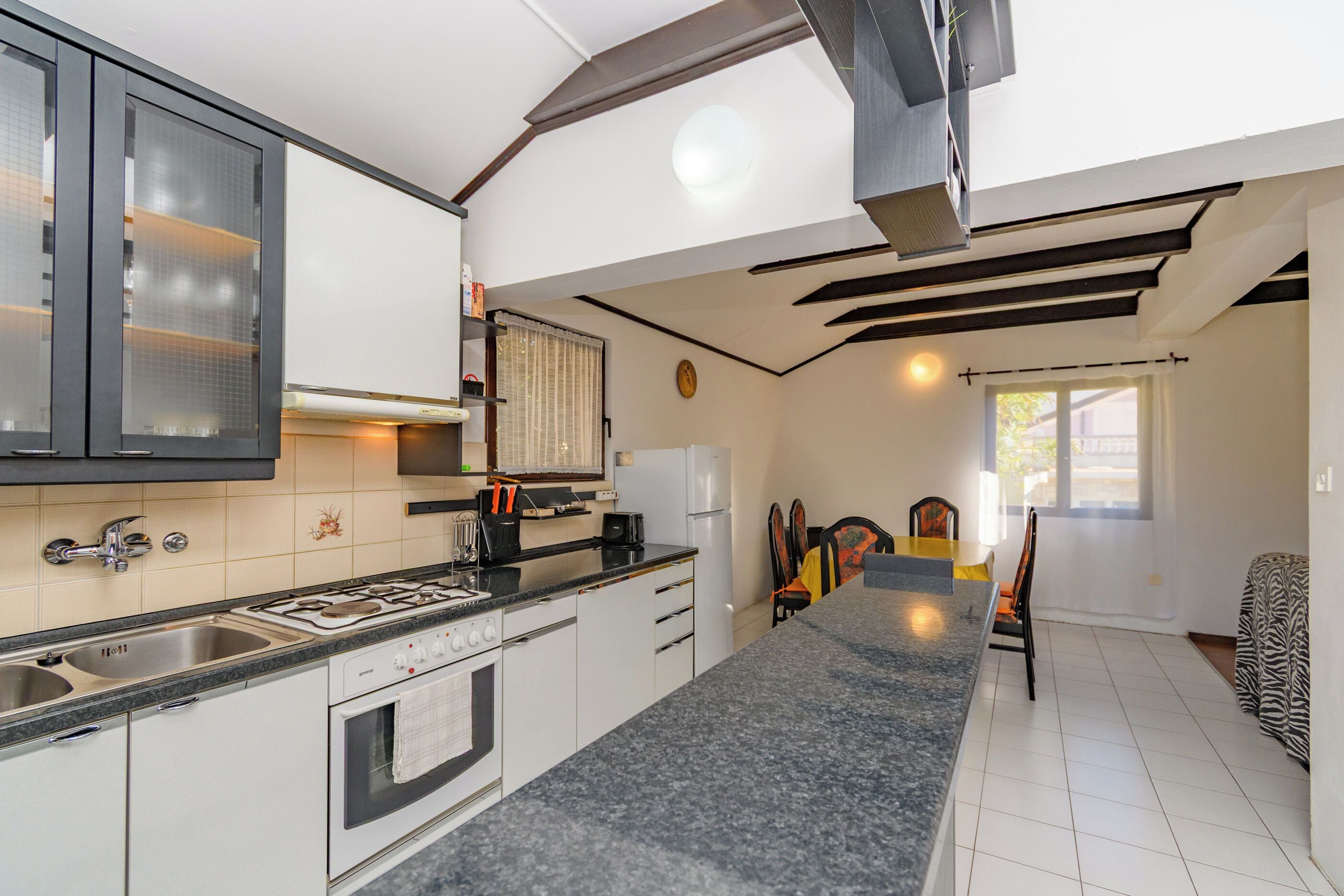 A modern kitchen with a granite countertop, stainless steel appliances, and a dining area with a table and chairs.