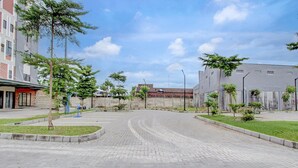 Un patio pavimentado con un sendero curvo, rodeado de edificios y pequeños árboles.