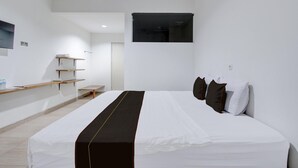 Una habitación de hotel moderna con una cama grande, un televisor montado y un diseño minimalista.