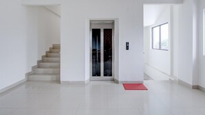 Un interior moderno con una escalera, un ascensor de vidrio y un tapete rojo.