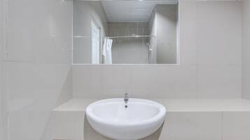 Ein Badezimmer mit einem weißen Waschbecken, einem Spiegel und einer Duschkabine.