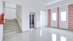 Een ruim, modern interieur met een trap, een brandblusser en een deur naar een andere kamer.