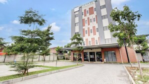 Een meerlaags hotel met een moderne gevel, een overdekte entree en een aangelegde binnentuin.