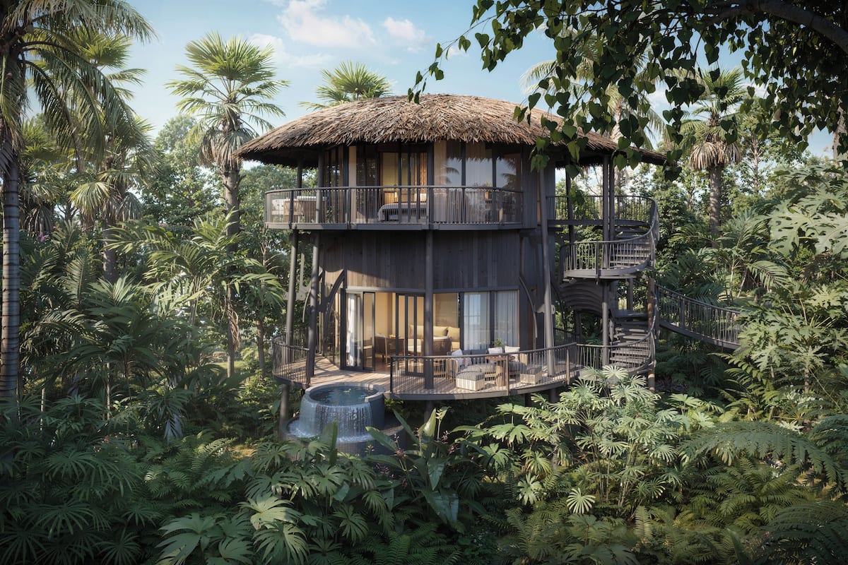 A multi-level wooden structure with balconies, surrounded by dense tropical foliage.