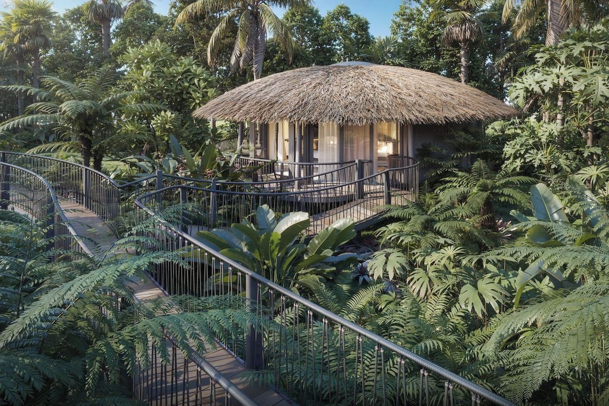 A thatched-roof structure surrounded by lush tropical vegetation, connected by a metal staircase.