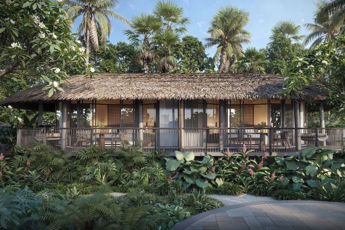 A thatched-roof structure with outdoor seating, surrounded by lush tropical vegetation.