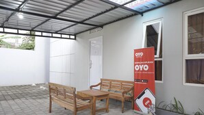 Un espacio al aire libre techado con un banco y una mesa de madera, una puerta blanca y un cartel promocional de OYO Hotels.