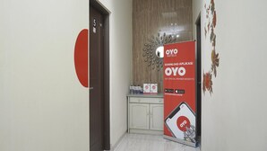 Un pasillo de hotel con una promoción de la aplicación OYO Hotels, una puerta con el número 5 y un adorno en la pared.