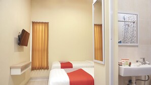 Habitación de hotel con dos camas, baño con lavabo y espejo.