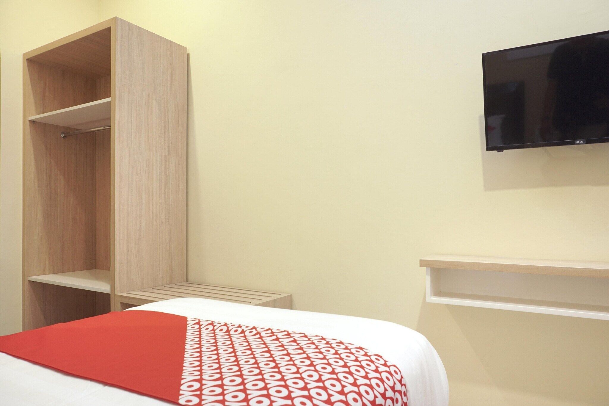 A hotel room with a bed, a wardrobe, a TV mounted on the wall, and a small table.
