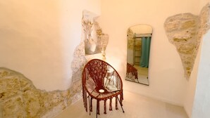 A room with a unique stone wall design, a wooden chair, and a mirror reflecting a bathroom. - Suite Ninfea – Historic Home in the Heart of Ostuni (Ostuni)