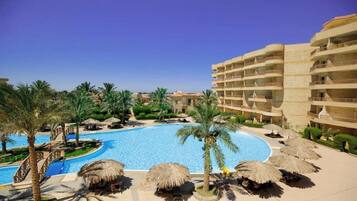 Ein Resort mit großem Pool, Palmen und einem mehrstöckigen Gebäude.