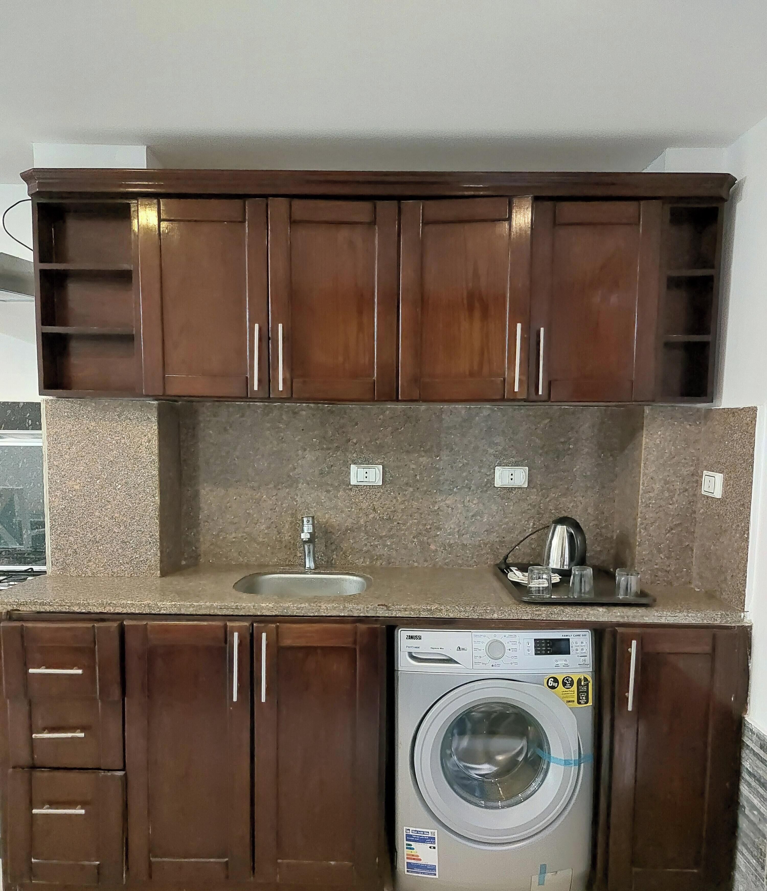 Eine Küche mit Holzausstattung, einer integrierten Waschmaschine und einem Spülbecken.