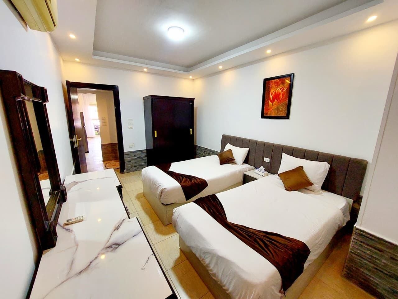 Habitación de hotel con dos camas, una encimera de mármol y un cuadro en la pared.