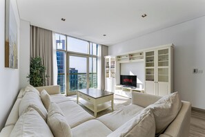 A modern living room with a large window, a flat-screen TV, and a white entertainment unit. - Chic 1BR APT in DIFC I 7-Min Drive to Burj Khalifa (Dubai)
