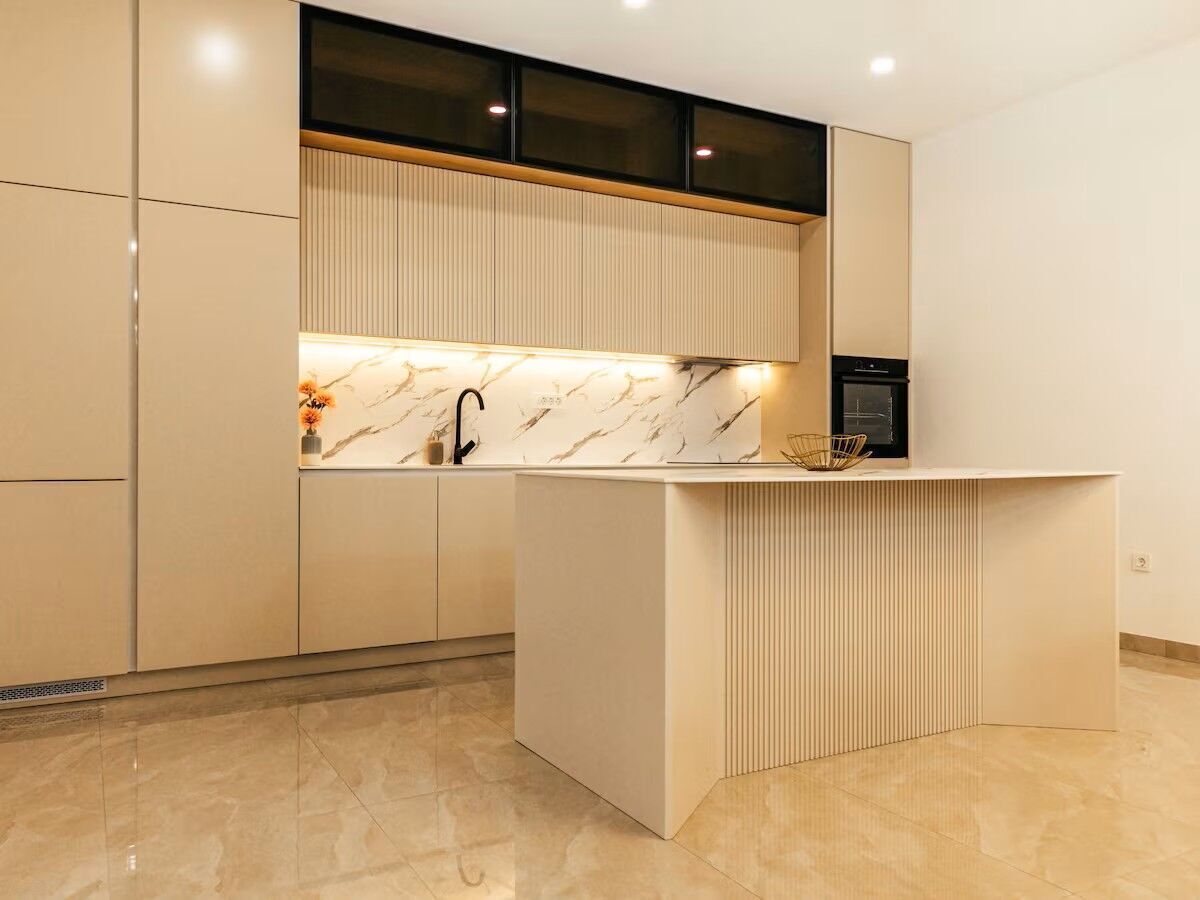 A modern kitchen with a marble countertop, a built-in oven, and a sleek island.
