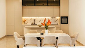 A modern dining area with a marble countertop, a central vase with flowers, and a built-in oven.