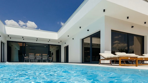 A modern house with a swimming pool, large windows, and outdoor seating.
