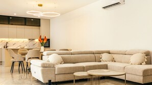 A modern living room with a sectional sofa, a round coffee table, and a dining area with chairs.