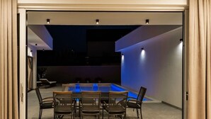 An indoor pool area with a table and chairs, surrounded by walls and a ceiling.
