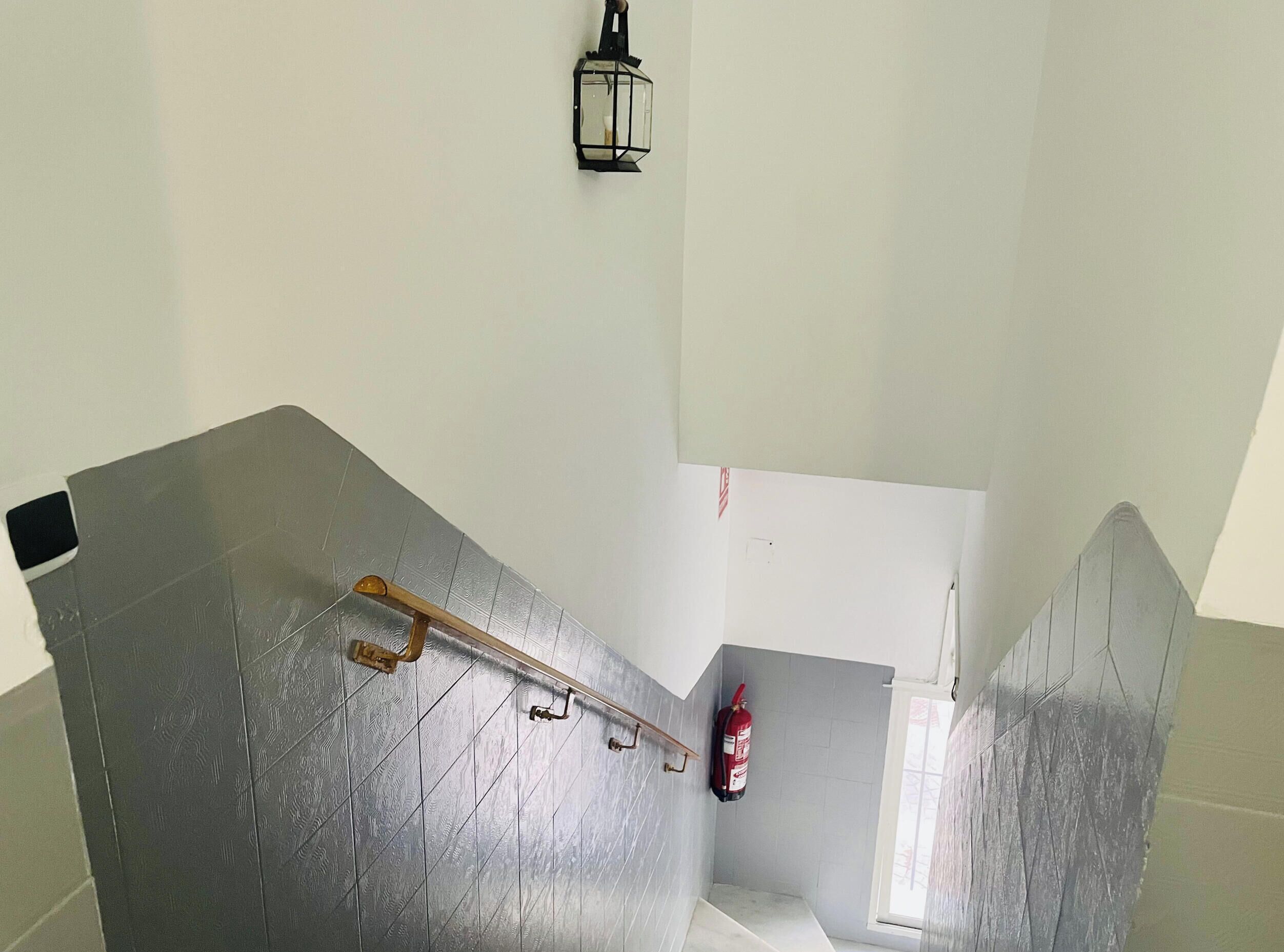 A staircase with a fire extinguisher and a wall-mounted light fixture.